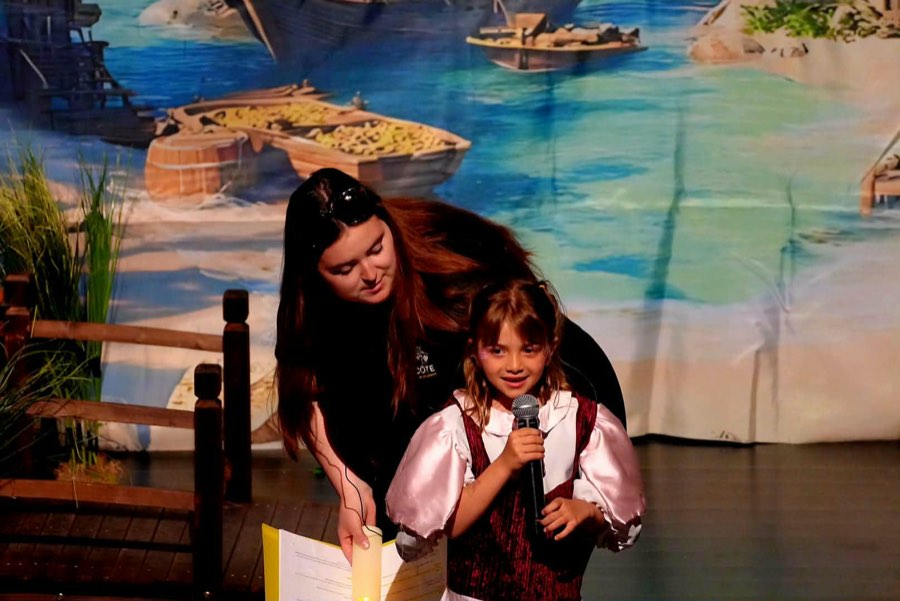 Une animatrice et une petite pirate lisent ensemble