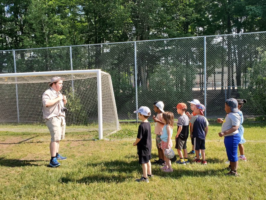 L’animateur explorateur rassemble les enfants pour une fête scolaire