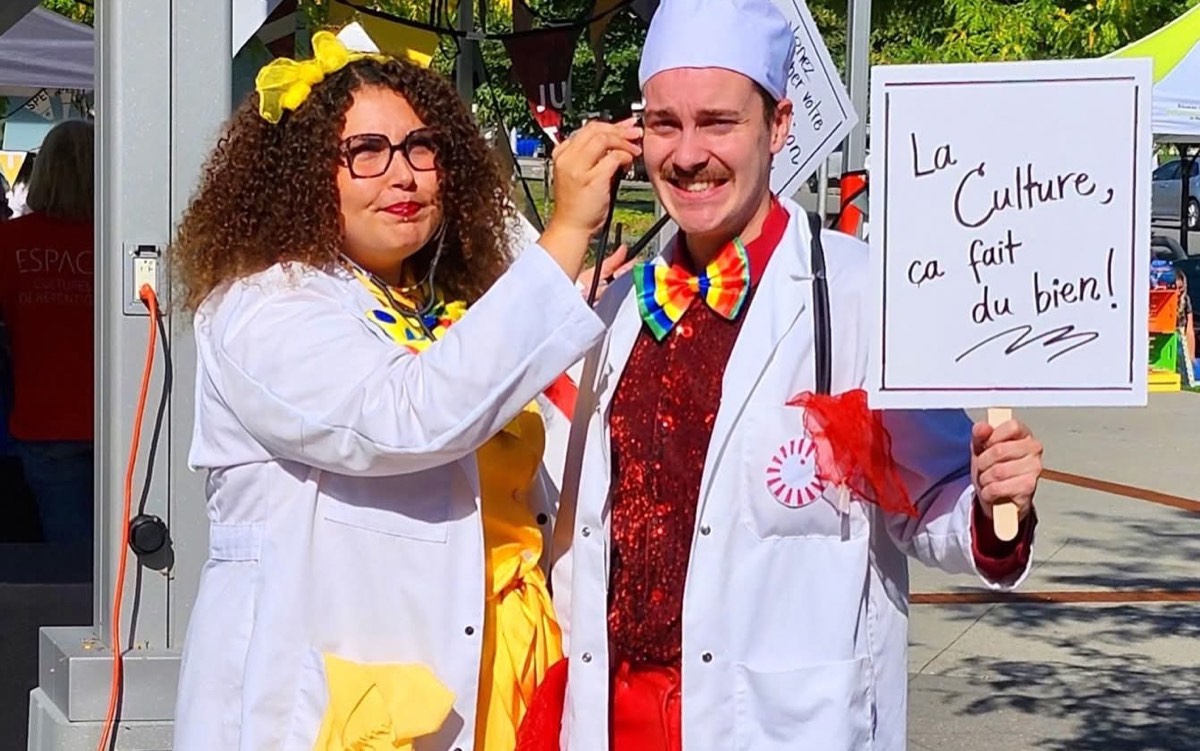 Deux personnages en sarrau tiennent une pancarte : La Culture, ça fait du bien!